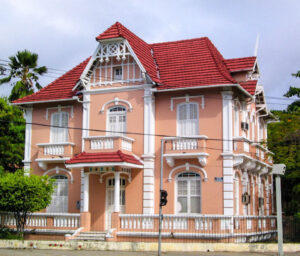 Fachada da casa de cultura alemâ, da Universidade Federal do Ceará. Prédio prédio antigo, na cor de rosa, com dois andares, com prtas e janelas compridas e estreitas, na cor branca, na parte frontal do térreo e primeiro andar